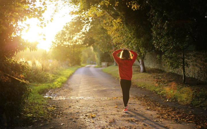 Mujer caminando al amanecer en otoño por un sendero arbolado en Pulborough, Inglaterra, en un entorno natural al aire libre.