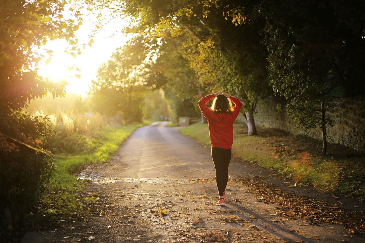 Mujer caminando al amanecer en otoño por un sendero arbolado en Pulborough, Inglaterra, en un entorno natural al aire libre.