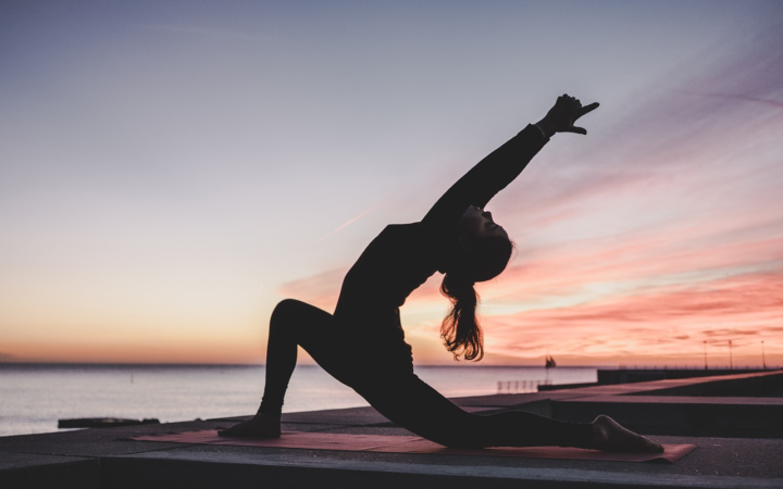 Mujer practicando yoga y meditación al aire libre durante el amanecer o atardecer en la naturaleza.