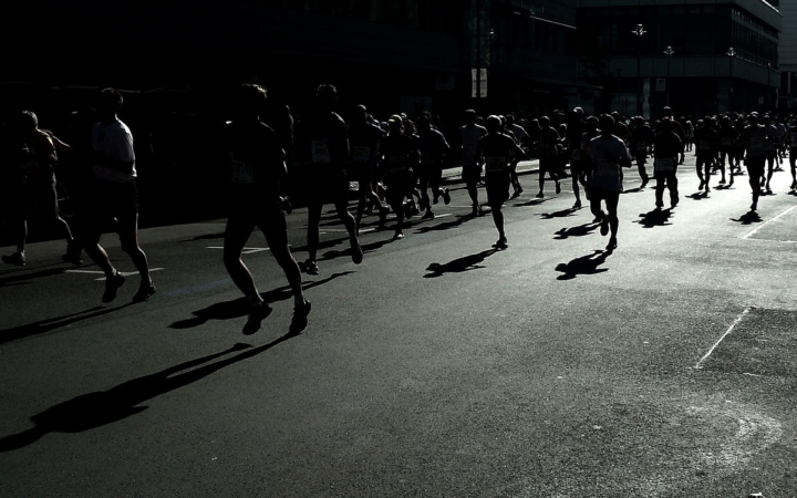 Corredor de maratón en blanco y negro, con contraluz y sombras marcadas, durante una competencia deportiva de resistencia.