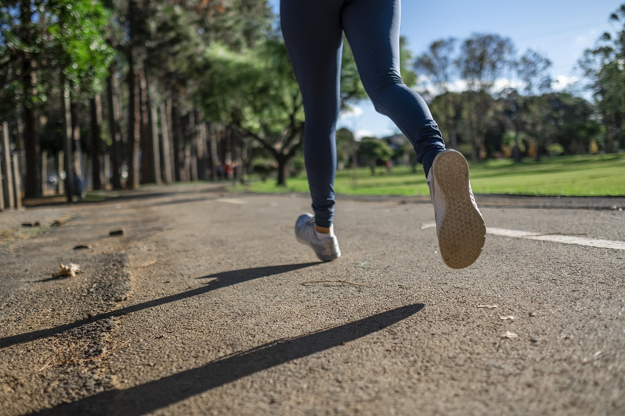 Mujer corriendo en una carrera deportiva al aire libre, en un parque, con enfoque en su velocidad y condición física.