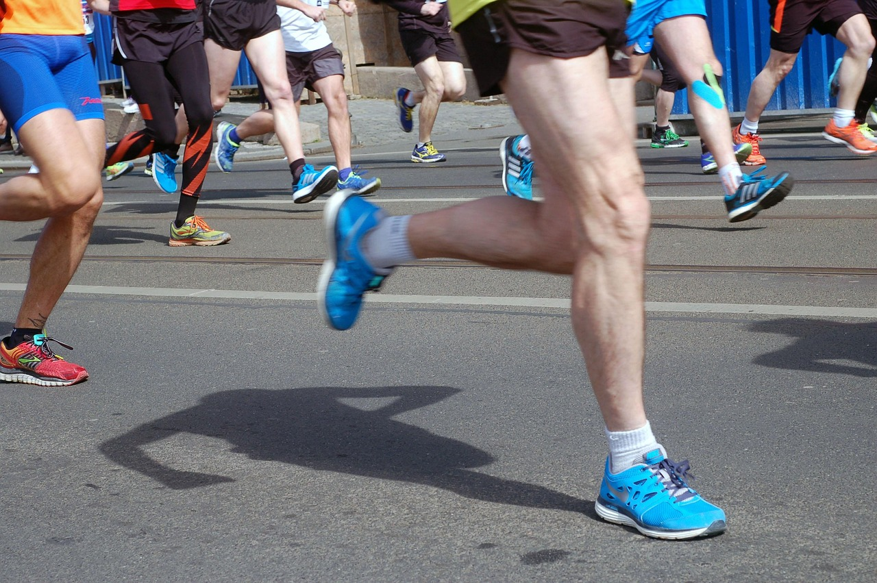 Persona corriendo en una carrera deportiva por la ciudad, con énfasis en pies y músculos de las piernas, relacionada con la salud.