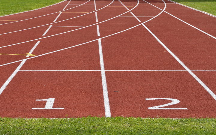 Pista de atletismo de tartán con marcas de salida y numeración, lista para una carrera de competencia deportiva.