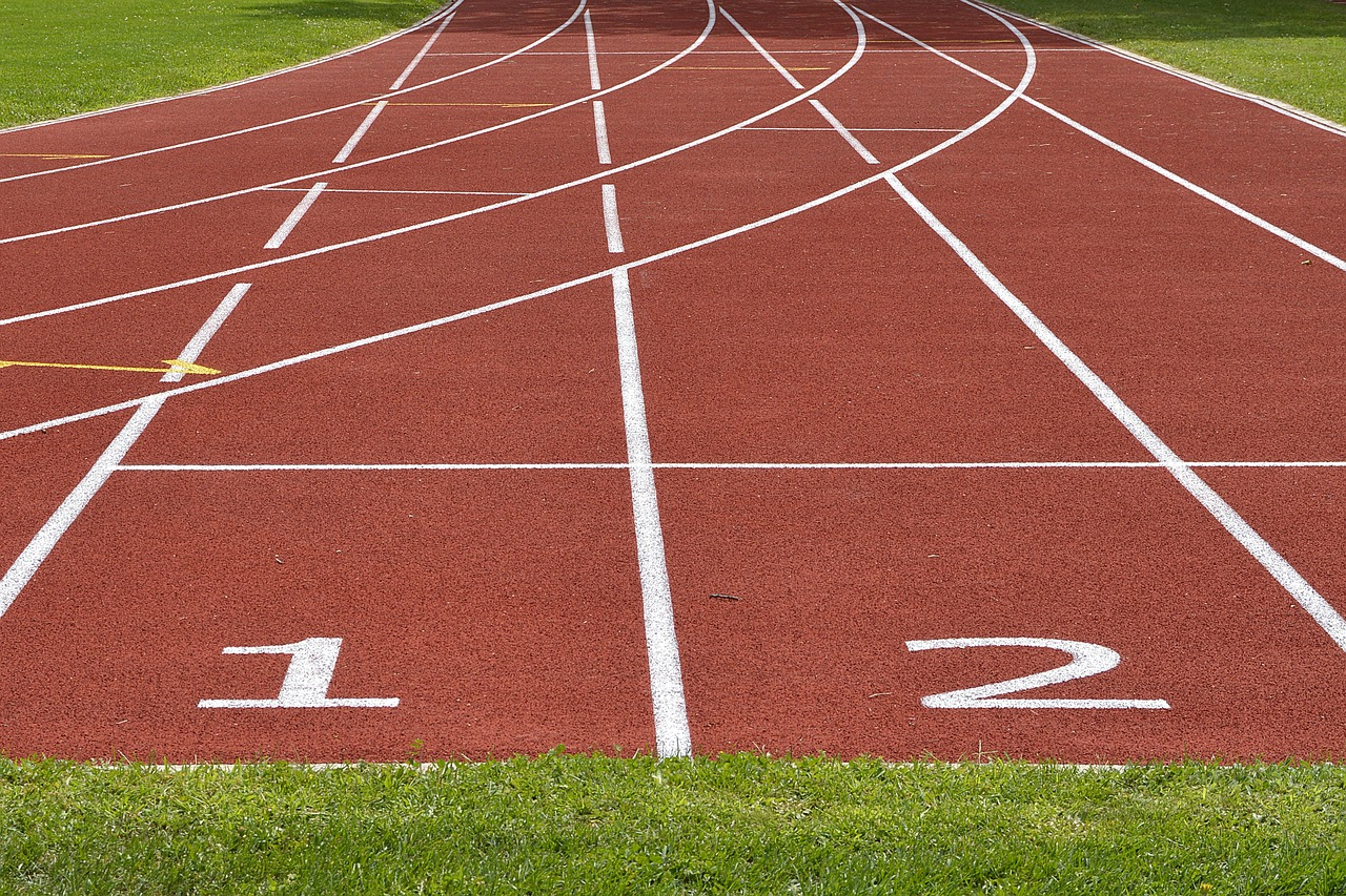 Pista de atletismo de tartán con marcas de salida y numeración, lista para una carrera de competencia deportiva.