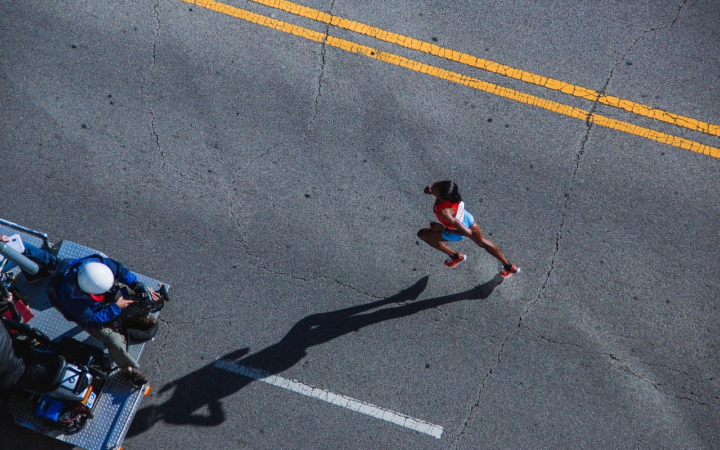 Corredora en competencia de maratón sobre asfalto, vista aérea de la carrera.