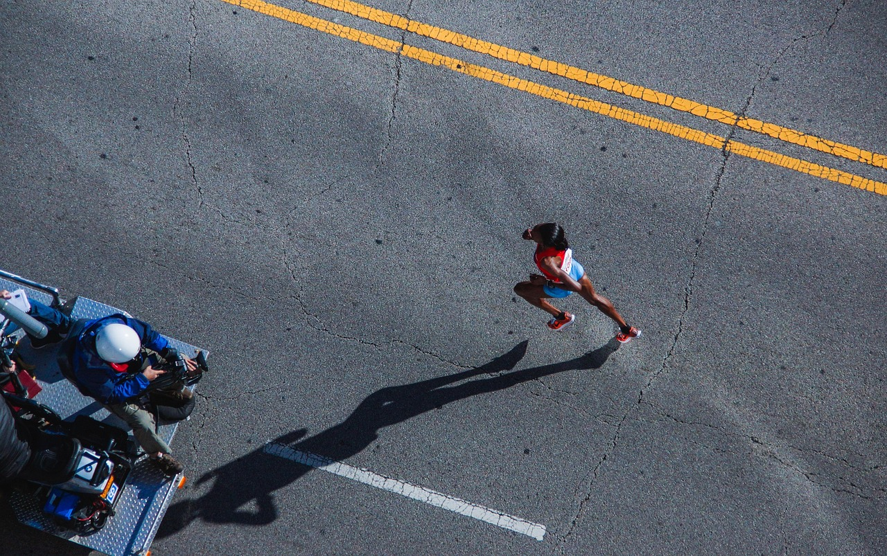 Corredora en competencia de maratón sobre asfalto, vista aérea de la carrera.