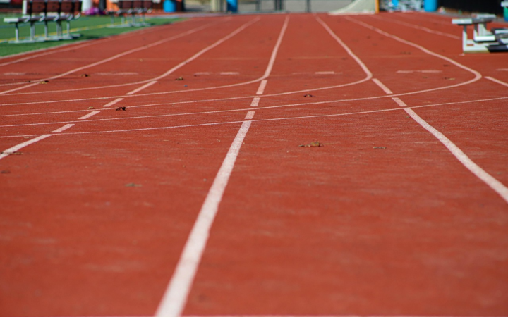 Corredor en una pista de atletismo, visto en perspectiva, durante una carrera de velocidad sobre su carril.