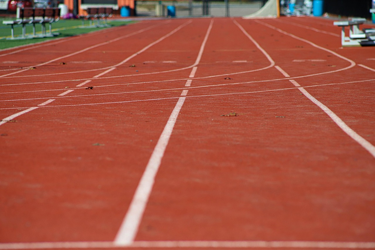 Corredor en una pista de atletismo, visto en perspectiva, durante una carrera de velocidad sobre su carril.