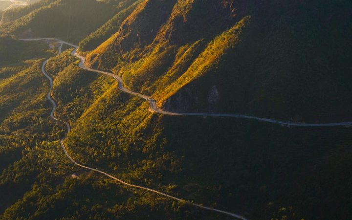 Carretera atravesando un paso montañoso al amanecer con montañas al fondo