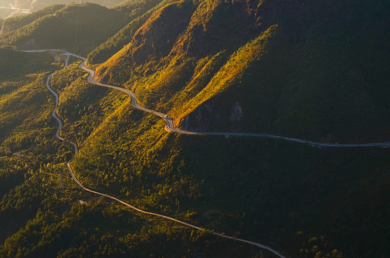 Carretera atravesando un paso montañoso al amanecer con montañas al fondo