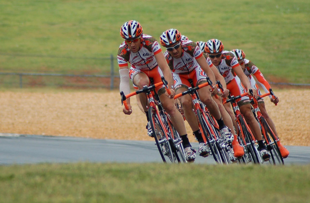 Grupo de ciclistas en una carrera de bicicletas, en acción y a alta velocidad, durante una competencia deportiva en equipo.