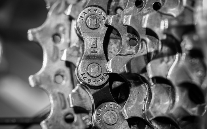 Engranajes metálicos y cadena de bicicleta, en blanco y negro, que muestran el mecanismo de transmisión de una bici.